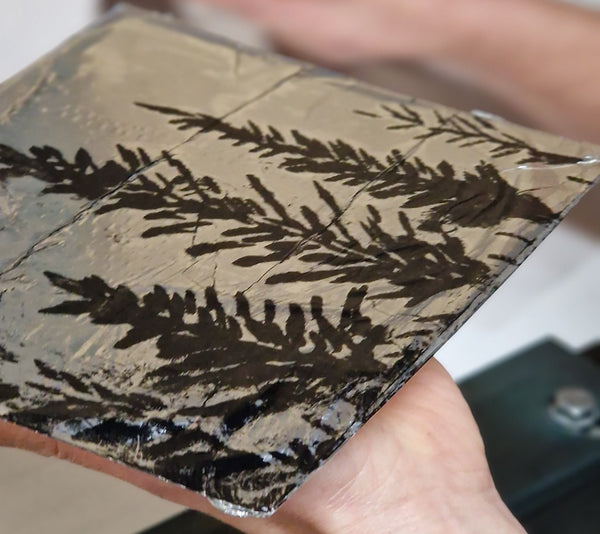 Close-up of a hand holding a textured clutch with leaf pattern.