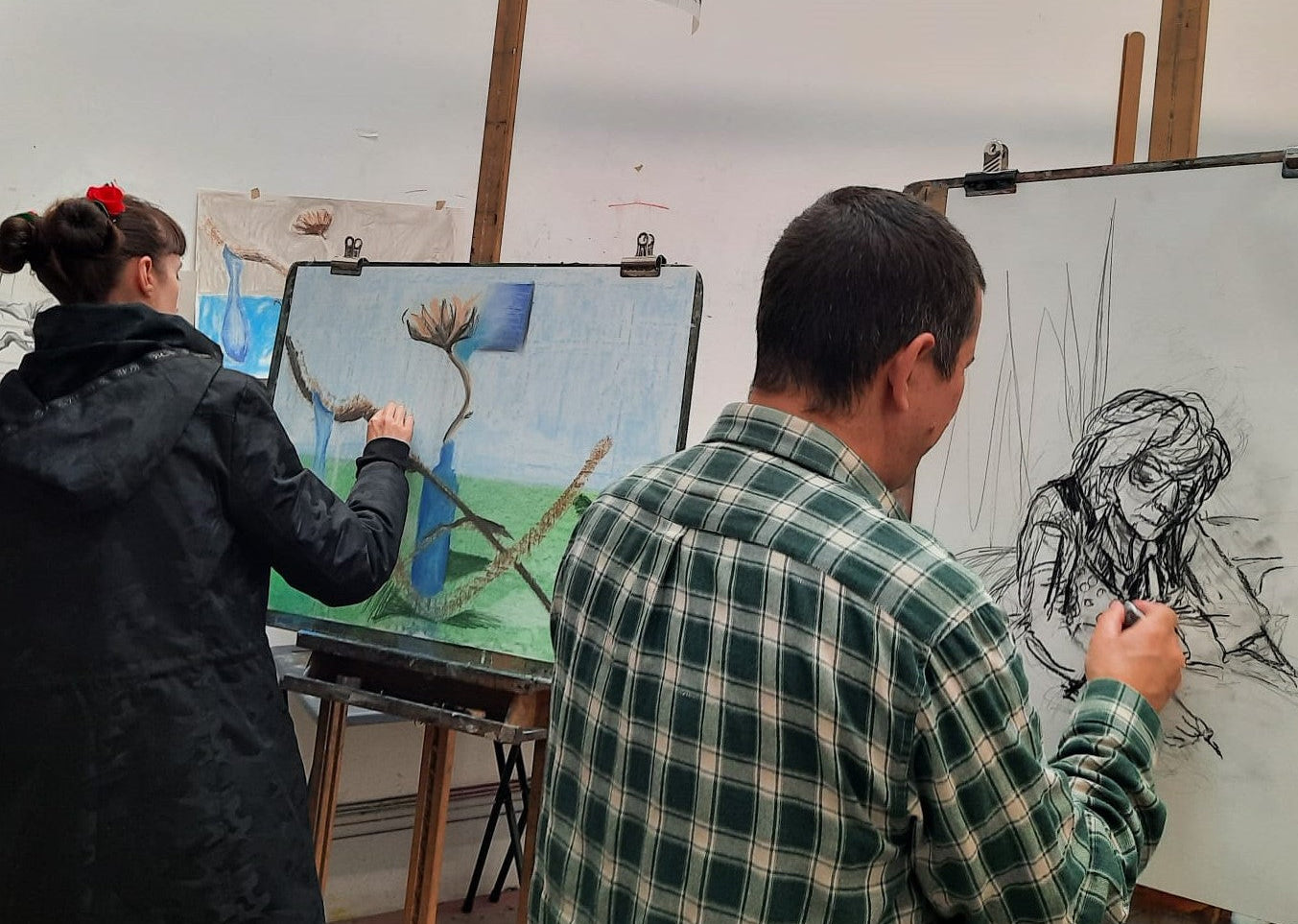 Two artists working on their paintings in a studio setting.